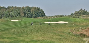 Budowa pola golfowego / galeria pól golfowych - dołek golfowy z approach i golfiści na polu golfowym Krakow Valley Golf & Country Club.